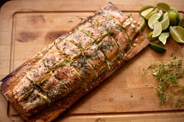 Delicious grilled salmon on wooden board garnished with lime and fresh herbs, healthy seafood meal