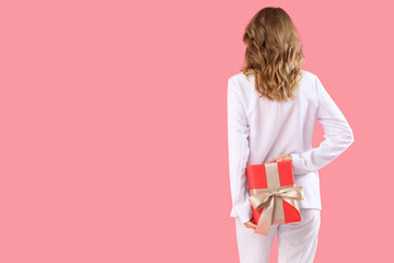 Beautiful young woman with gift box on pink background, back view