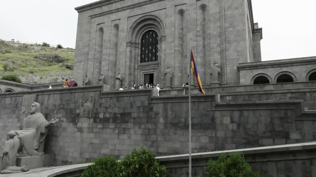 Armenian flag in front of the Matenadaran, with many visitors on the steps and plaza in Yerevan