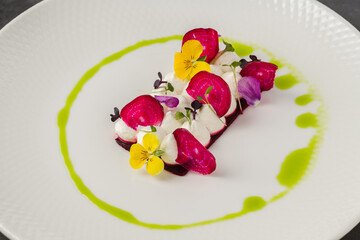 Colorful beetroot slices with goat cheese, garnished with edible flowers