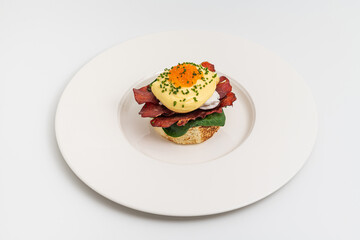 Eggs Benedict with poached egg, bacon, spinach and hollandaise sauce
