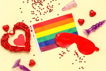 Rainbow LGBT flag with sex toys and heart shaped decor on beige background. Valentine's Day...