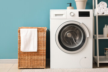 Wicker basket and washing machine near blue wall in laundry room