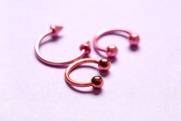 Pink circular barbells for piercing on lilac background