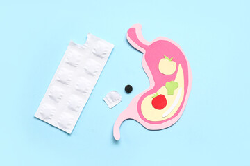 Paper human stomach and activated carbon pills on color background