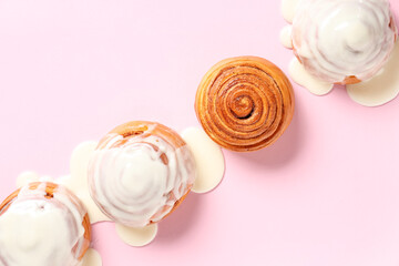 Tasty cinnamon rolls with glaze on pink background