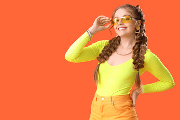 Happy smiling young woman with braids and sunglasses on orange background
