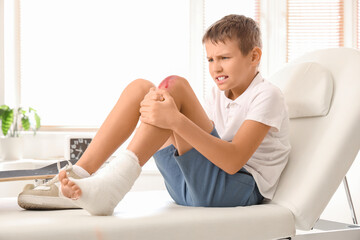 Little boy with injured leg sitting on couch in clinic
