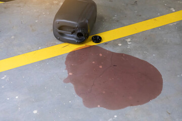 Car oil leak on concrete garage floor with yellow parking line