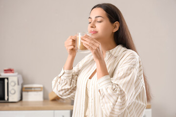 Pretty young woman with cup of hot coffee at home
