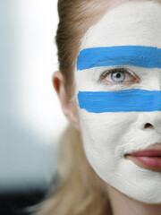 An individual's face is adorned with flag of Argentina as a gesture of passionate backing for their...