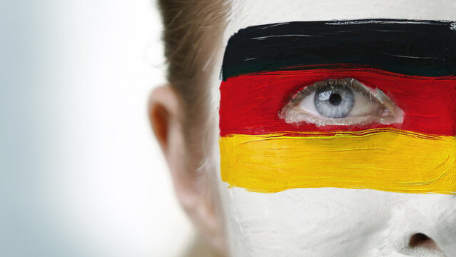 Close-up of face painted in German flag colors expressing patriotic emotion, fan passion, and national sports pride. Represents loyalty, excitement, and team support during a sporting event.