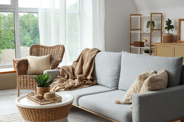 Interior of stylish living room with wicker chair, table and comfortable sofa
