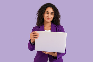 Portrait of beautiful African-American businesswoman with laptop on purple background