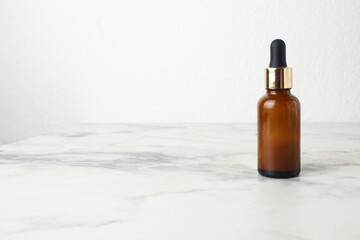Brown bottle with pipette on white light background. Cosmetics for the face and body