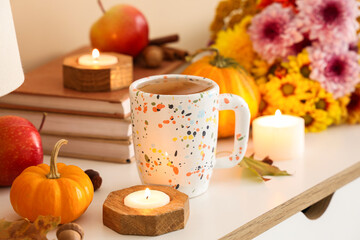 Cup of green tea, candles and books on chest of drawers in room