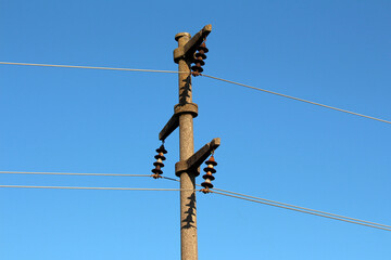 Tall concrete utility pole with ceramic disc insulators and power lines stretches across a clear...