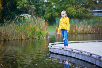 Fototapeta premium Cheerful little girl enjoying her walk in autumn park in Paris, France.