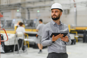 Industrial engineer holding tablet and supervising production line in factory