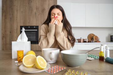 Ill young woman with runny nose in kitchen