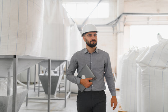 Engineer inspecting flour production in factory using laptop