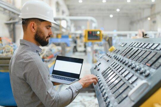 Industrial engineer operating machinery with laptop in factory