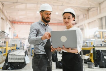 Engineers discussing production using laptop in factory