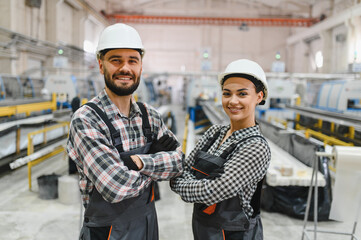 Smiling industrial workers posing with arms crossed in factory