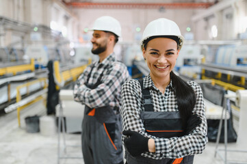 Smiling industrial workers posing with crossed arms in factory