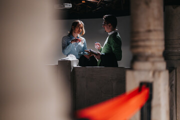 People examining a tablet display inside a museum, surrounded by architectural structures and...