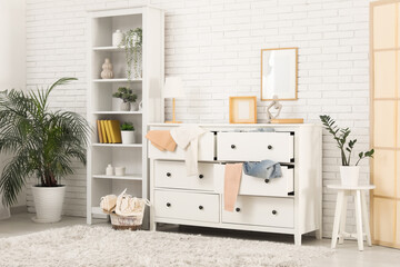 Interior of messy living room with shelving unit, scattered clothes and commode