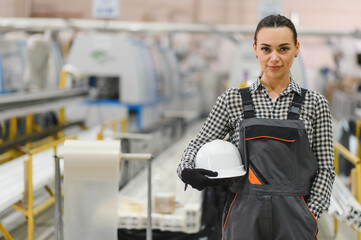 Female factory worker holding hardhat in pvc windows and doors plant