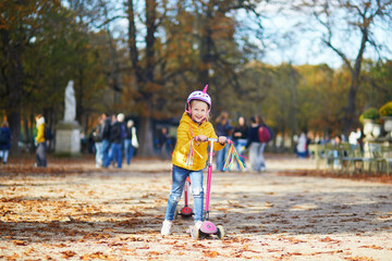 Fototapeta premium Cheerful little girl enjoying her walk in autumn park in Paris, France.