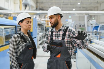 Supervisor explaining production process to female worker in factory