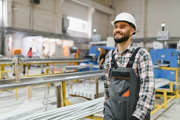 Smiling factory worker walking in pvc and aluminum window production line
