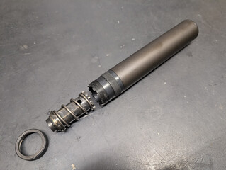 Disassembled 9mm pistol suppressor on a workbench. Cleaning and maintenance of firearm accessories...