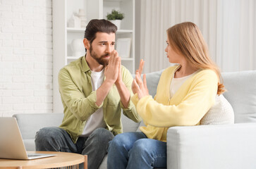 Young woman refusing to forgive her husband on sofa at home