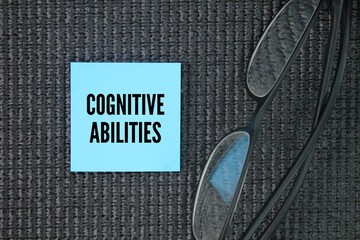 Glasses and colored paper with the word cognitive abilities. the mental processes involved in...