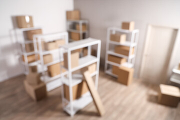 Blurred view of warehouse with shelf units, cardboard boxes and door