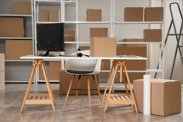 Interior of warehouse with shelf units, cardboard boxes and workplace