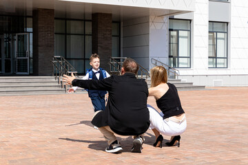 Happy family. Caring mother and father meet cheerful child boy, with backpack running in their...