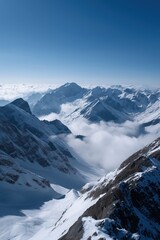 Fototapeta premium Snow-capped mountain peaks and vast cloudscape under clear blue sky