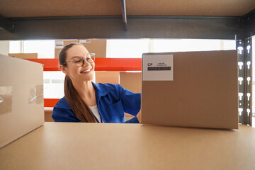 Female worker taking parcel from shelf in warehouse