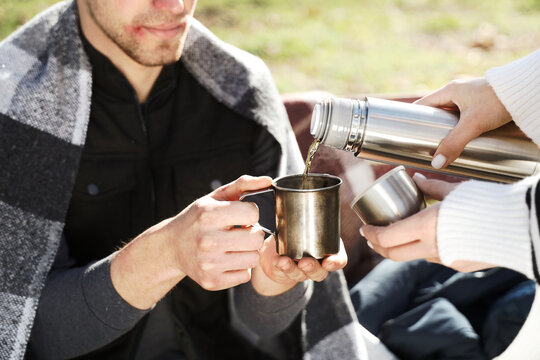 Homeless man with woman pouring hot tea in park, closeup - Powered by Adobe