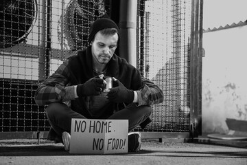 Homeless man and cardboard with text NO HOME NO FOOD on street