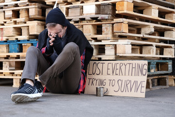 Frozen homeless man and cardboard with text LOST EVERYTHING TRYING TO SURVIVE on street