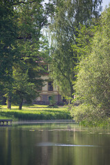 A peaceful view of a historic building partially hidden among lush green trees, reflected in the...