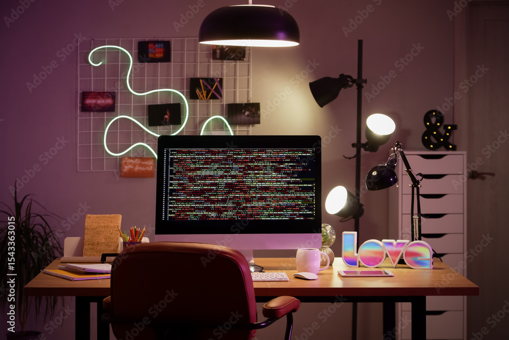 Poster programmer's desk with computer and glowing lamps in office at night