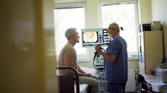 Doctor explaining colonoscopy results to patient using monitor images.