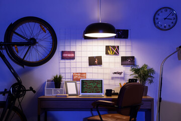 Interior of dark programmer's office with workplace, bicycle and glowing lamp at night